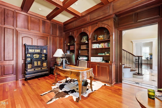 office area featuring coffered ceiling, wooden walls, built in features, beam ceiling, and light hardwood / wood-style floors