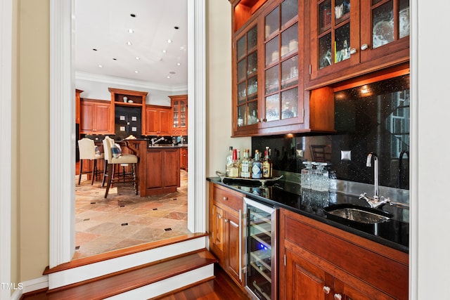 bar featuring sink, decorative backsplash, dark stone countertops, ornamental molding, and beverage cooler