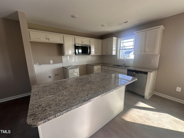 kitchen with tasteful backsplash, a kitchen island, sink, white cabinetry, and appliances with stainless steel finishes