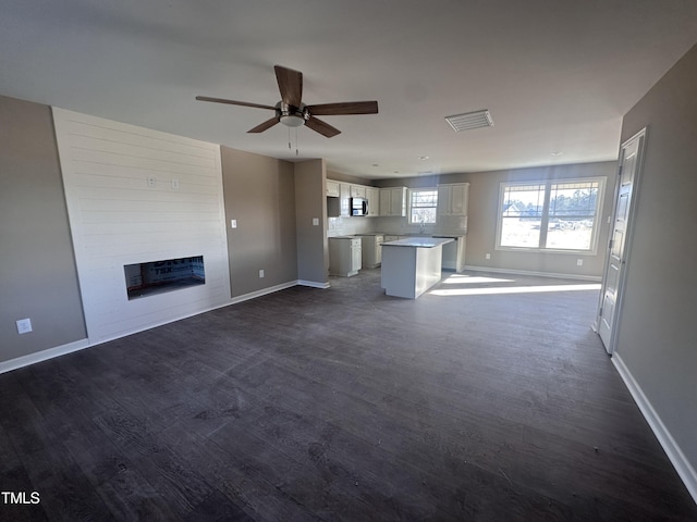 unfurnished living room with ceiling fan and a fireplace