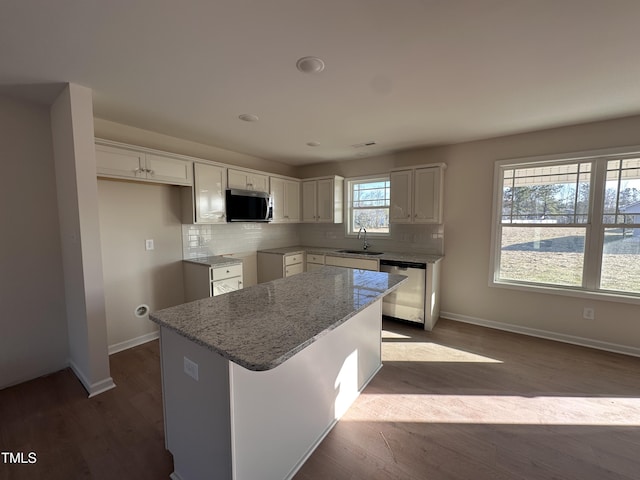 kitchen with tasteful backsplash, a center island, appliances with stainless steel finishes, white cabinets, and light stone counters