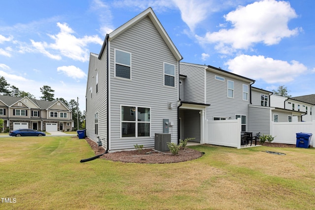 rear view of house featuring a garage, central AC unit, and a yard