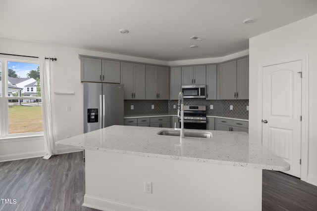 kitchen featuring appliances with stainless steel finishes, a wealth of natural light, light stone counters, and dark hardwood / wood-style floors