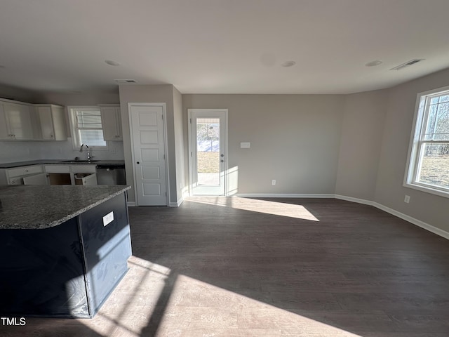 kitchen featuring white cabinets, dark hardwood / wood-style flooring, dark stone counters, sink, and stainless steel dishwasher