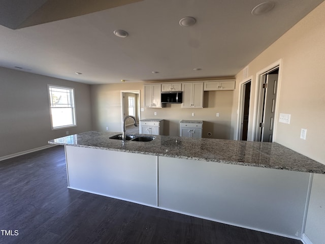 kitchen with white cabinets, dark hardwood / wood-style flooring, sink, and light stone counters