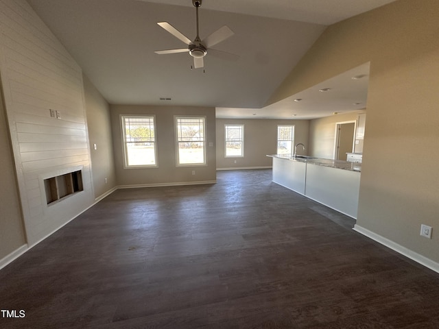 unfurnished living room with ceiling fan, dark wood-type flooring, a large fireplace, lofted ceiling, and sink