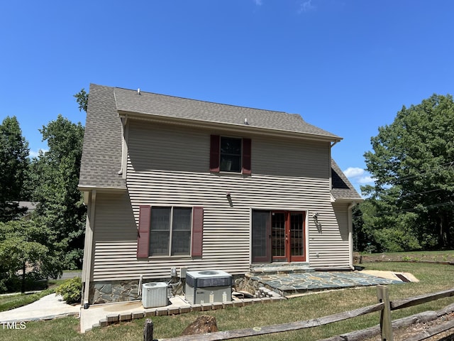 rear view of house with central AC and a lawn