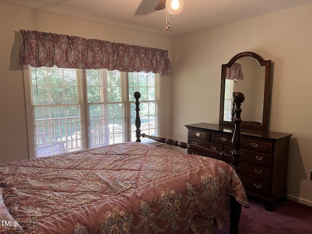 bedroom with ceiling fan, dark carpet, and a textured ceiling