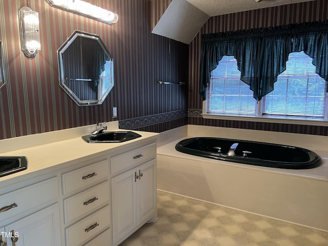 bathroom featuring vanity, a tub to relax in, and a textured ceiling