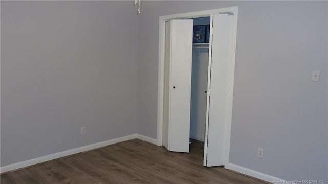 unfurnished bedroom with dark hardwood / wood-style flooring and a closet