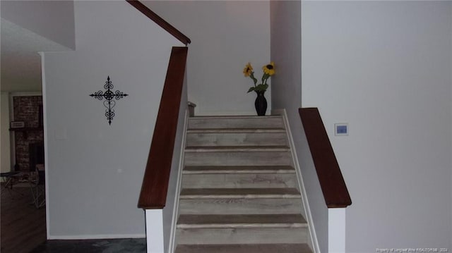 staircase featuring a brick fireplace