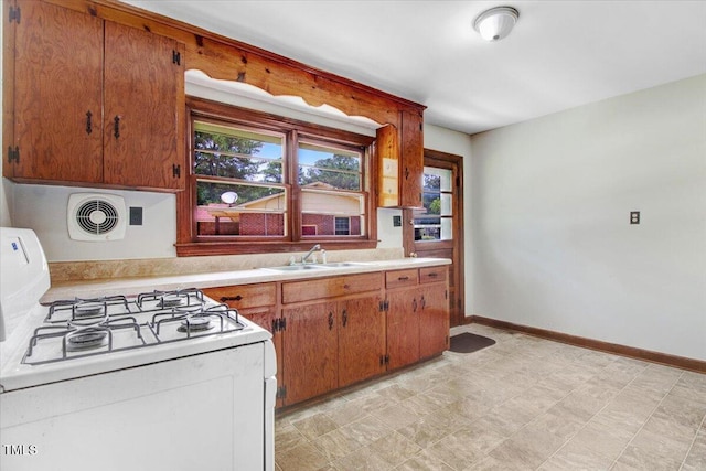 325 Bell St, Enfield, NC 27823 - kitchen with white gas range, light countertops, and brown cabinets