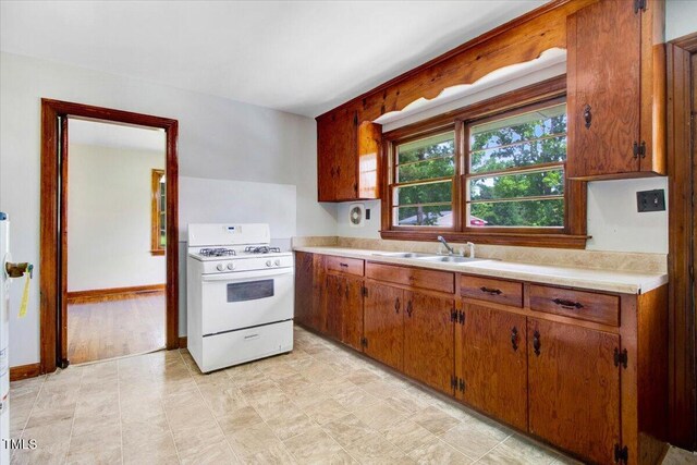 325 Bell St, Enfield, NC 27823 - kitchen with white range with gas cooktop, light countertops, and brown cabinetry