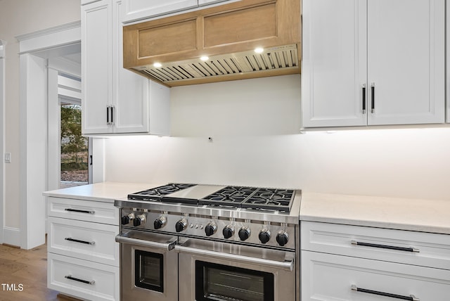 kitchen with white cabinetry, hardwood / wood-style flooring, range with two ovens, and custom range hood