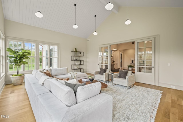 living room with beam ceiling, high vaulted ceiling, a healthy amount of sunlight, and light wood-style floors