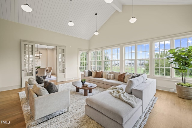 living area featuring baseboards, high vaulted ceiling, plenty of natural light, and wood finished floors