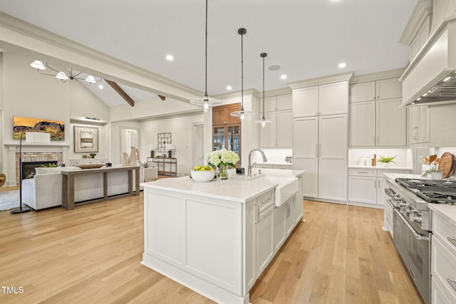 kitchen with a sink, stovetop, lofted ceiling with beams, open floor plan, and custom exhaust hood