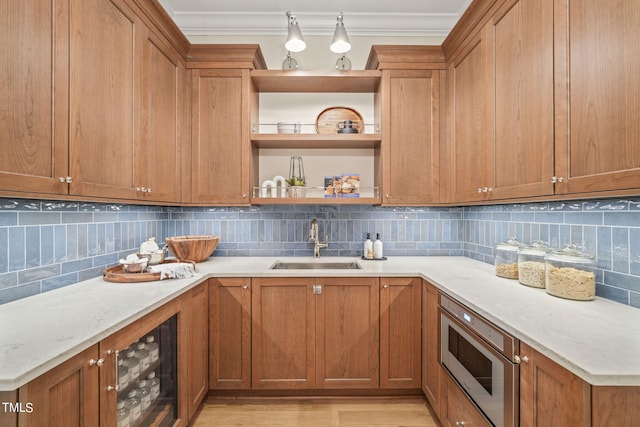 kitchen featuring ornamental molding, stainless steel microwave, a sink, open shelves, and brown cabinets
