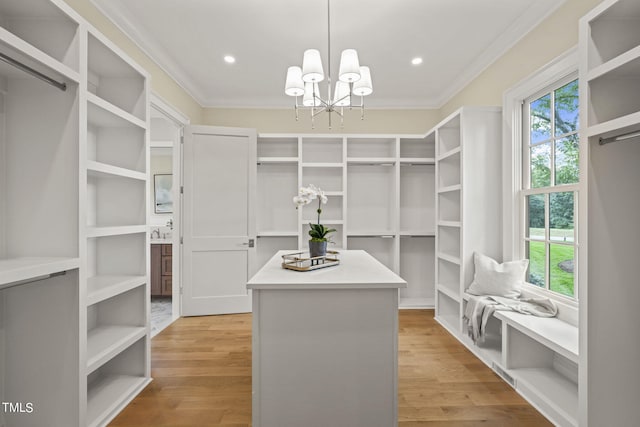 walk in closet with an inviting chandelier and light wood-style floors