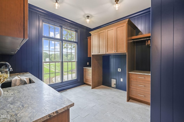 interior space featuring ornamental molding, a decorative wall, visible vents, and a sink