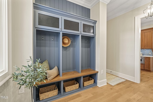 mudroom with crown molding, baseboards, light wood-type flooring, and an inviting chandelier