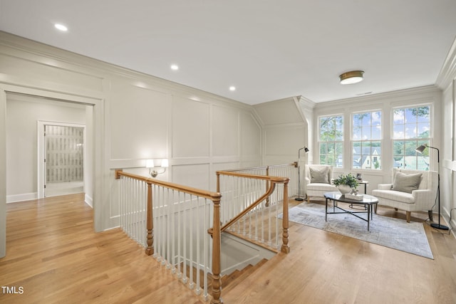 sitting room with an upstairs landing, a decorative wall, and crown molding