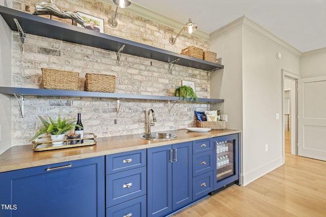 bar with a sink, indoor wet bar, crown molding, beverage cooler, and light wood-style floors