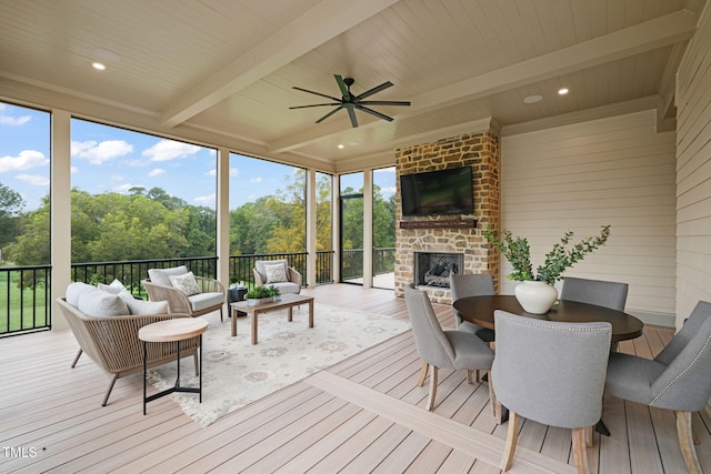 sunroom featuring an outdoor living space with a fireplace, a ceiling fan, and beam ceiling