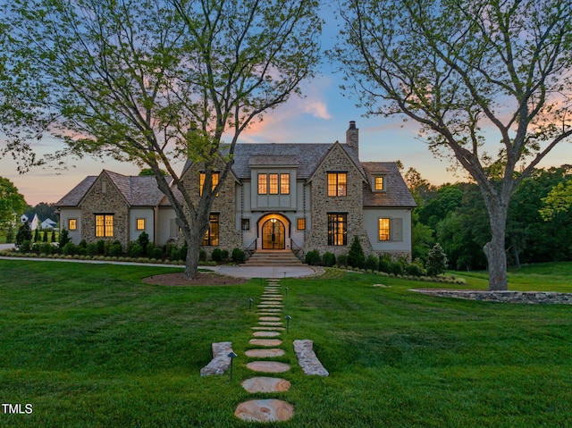 view of front of property featuring a chimney, a front lawn, and stone siding
