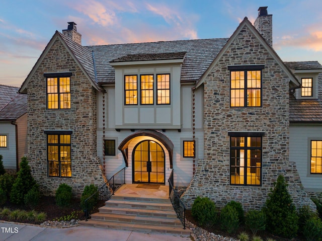 french country home with a chimney and stone siding
