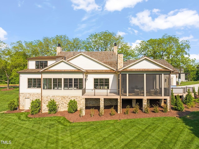 rear view of property featuring a chimney, a yard, and a sunroom