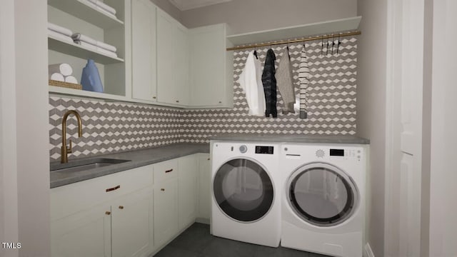 laundry area with dark tile patterned floors, washing machine and clothes dryer, a sink, and cabinet space