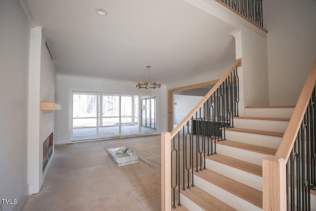 stairway with concrete flooring and a notable chandelier