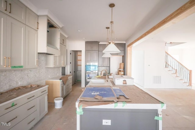 kitchen featuring sink, a kitchen island with sink, pendant lighting, gray cabinets, and decorative backsplash