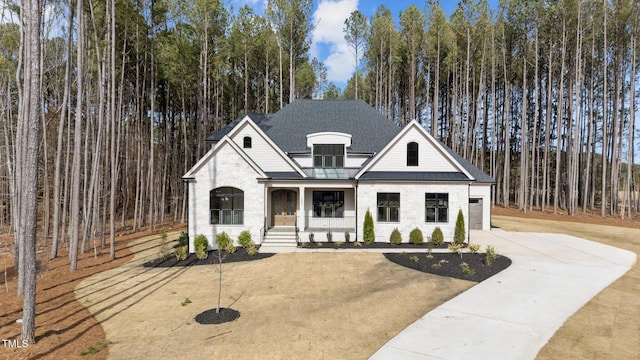 view of front of property featuring roof with shingles, a standing seam roof, metal roof, stone siding, and driveway