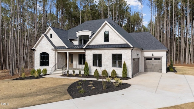 view of front of home with driveway, roof with shingles, an attached garage, a standing seam roof, and covered porch