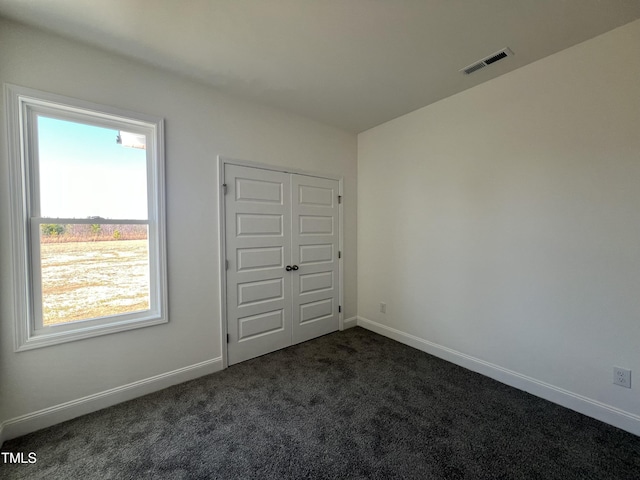 unfurnished bedroom featuring a closet and dark colored carpet