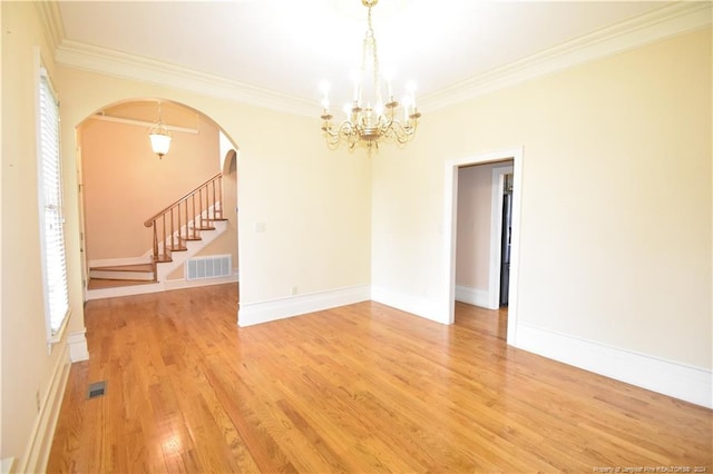 unfurnished room with a notable chandelier, light wood-type flooring, and crown molding