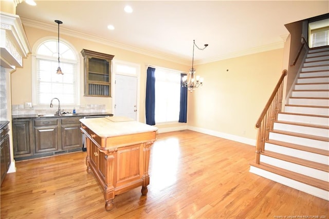 kitchen with a center island, sink, light hardwood / wood-style flooring, ornamental molding, and a chandelier