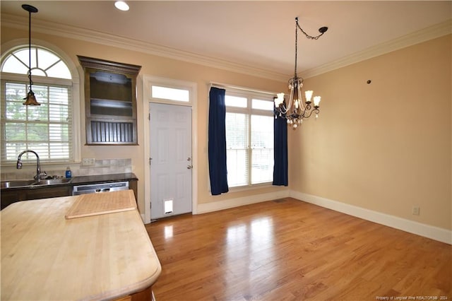 kitchen with wood-type flooring, plenty of natural light, ornamental molding, and sink