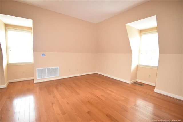 additional living space featuring wood-type flooring and vaulted ceiling