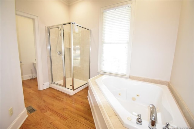 bathroom with plenty of natural light, shower with separate bathtub, and hardwood / wood-style flooring