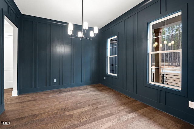 unfurnished dining area with hardwood / wood-style flooring and a chandelier