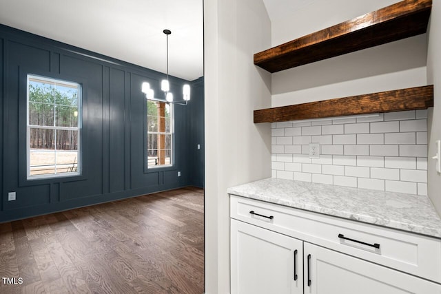 kitchen featuring white cabinetry, dark hardwood / wood-style flooring, hanging light fixtures, light stone counters, and french doors
