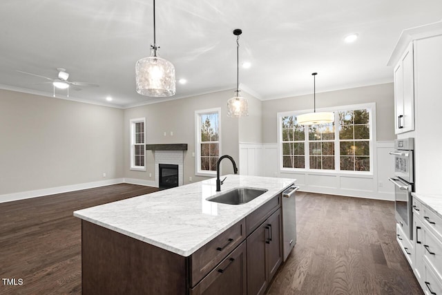 kitchen with white cabinetry, a fireplace, sink, and pendant lighting