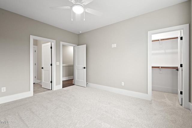 unfurnished bedroom featuring ceiling fan, a spacious closet, light colored carpet, and a closet