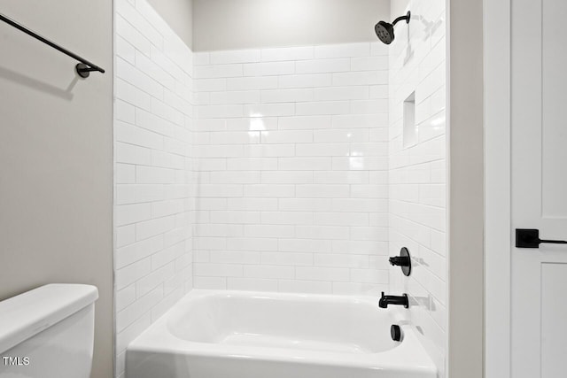 bathroom featuring tiled shower / bath combo and toilet