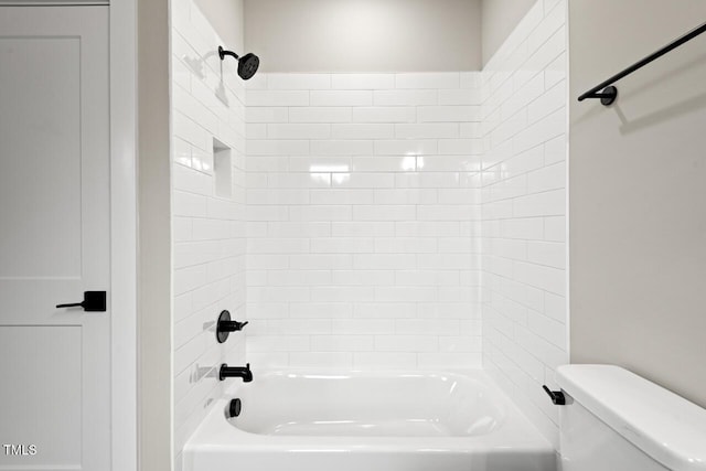 bathroom with toilet and tiled shower / bath