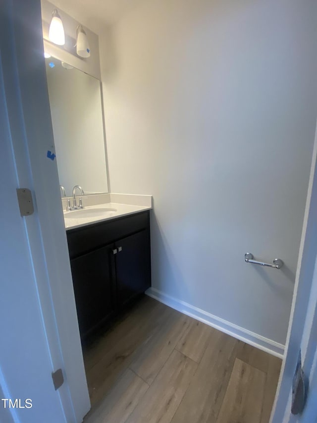 bathroom with wood finished floors, vanity, and baseboards