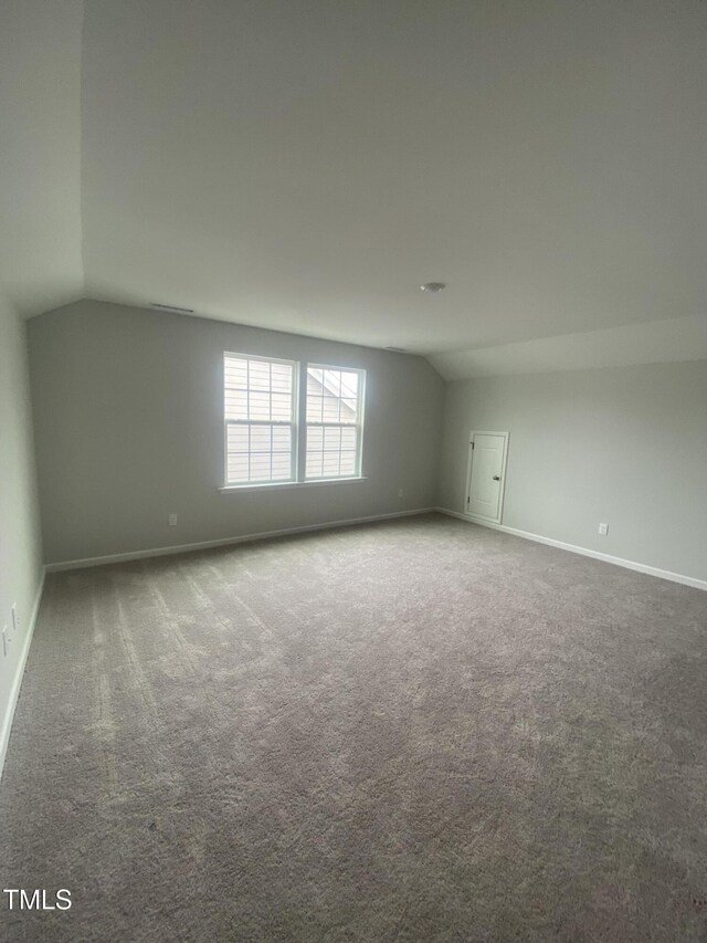 unfurnished room featuring lofted ceiling, carpet floors, and baseboards